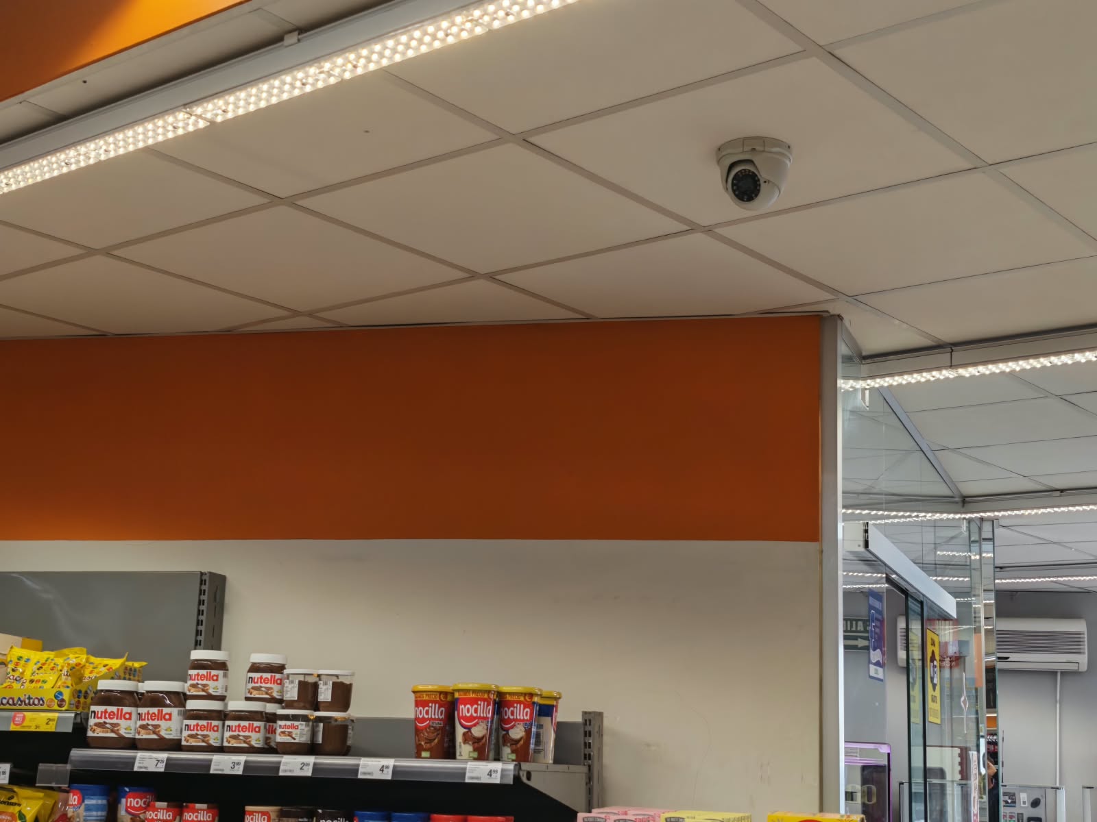 Cámara domo de videovigilancia cableada integrada en el techo técnico de una tienda de alimentación en Alaquàs
