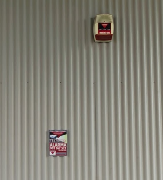 Sirena exterior de alarma y cartel de zona vigilada en una gasolinera de Alaquàs