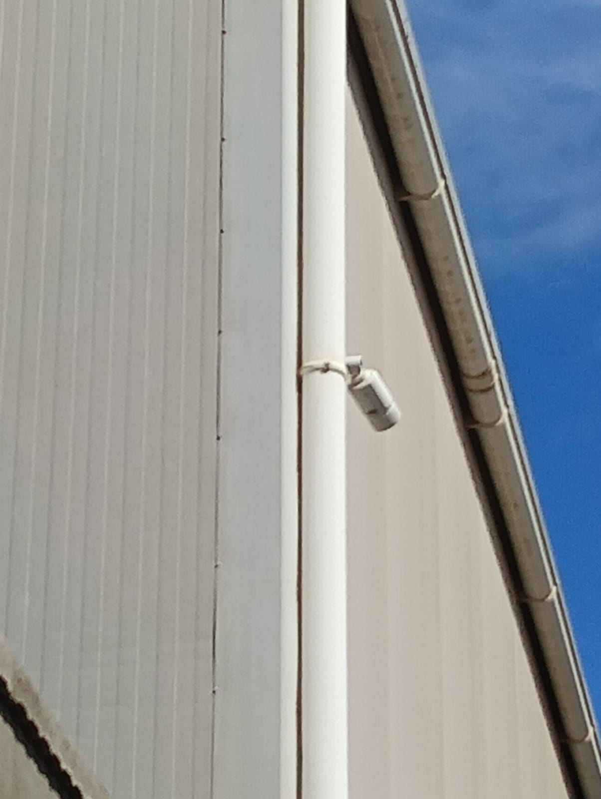 Cámara de videovigilancia exterior instalada en la fachada de una nave de una jamonera en Benaguacil