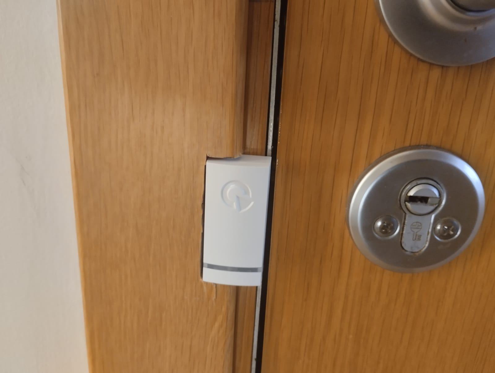 Sensor de apertura de la alarma instalado en el marco de la puerta de un piso en Valencia, junto a la cerradura